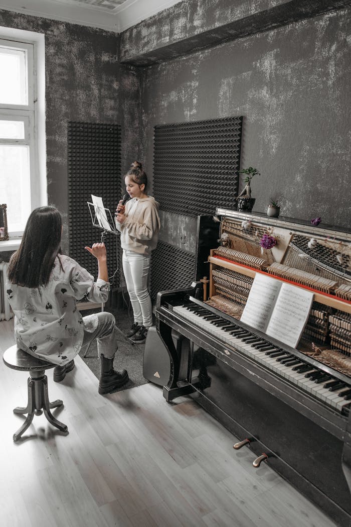 A music teacher guides a girl in an indoor piano lesson.